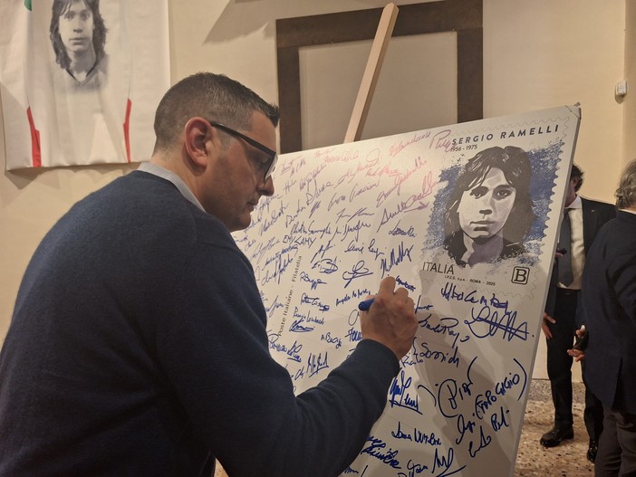 Francesco Attolini firma una maxi cartolina con la riproduzione del francobollo dedicato a Sergio Ramelli